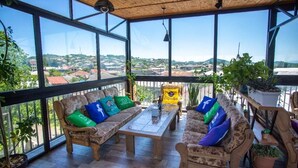 A spacious balcony with wooden furniture, potted plants, and a clear view of the cityscape. - Hotel Terrace Kutaisi (Kutaisi)