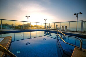 A swimming pool with clear water, surrounded by glass railings, and equipped with outdoor furniture. - UPG Hotel - Ubatuba Praia Grande Hotel (Ubatuba)