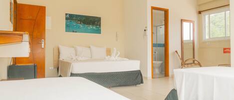 A hotel room with a bed, a desk, a chair, a bathroom, and a painting on the wall.
