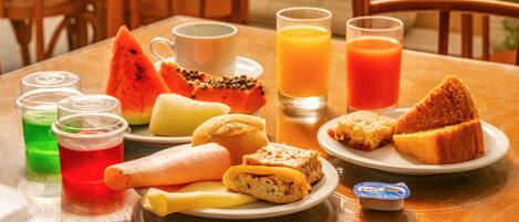 A breakfast table with various food items and drinks.