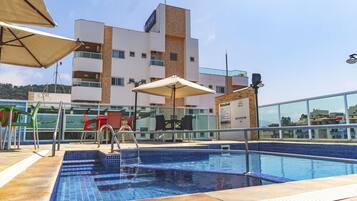 Zona de piscina en la azotea con vista despejada a un edificio de hotel al fondo.