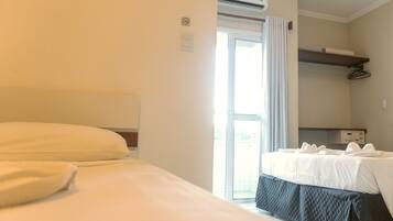 Habitación de hotel con una cama grande, una cama más pequeña, un escritorio y una ventana con cortinas.