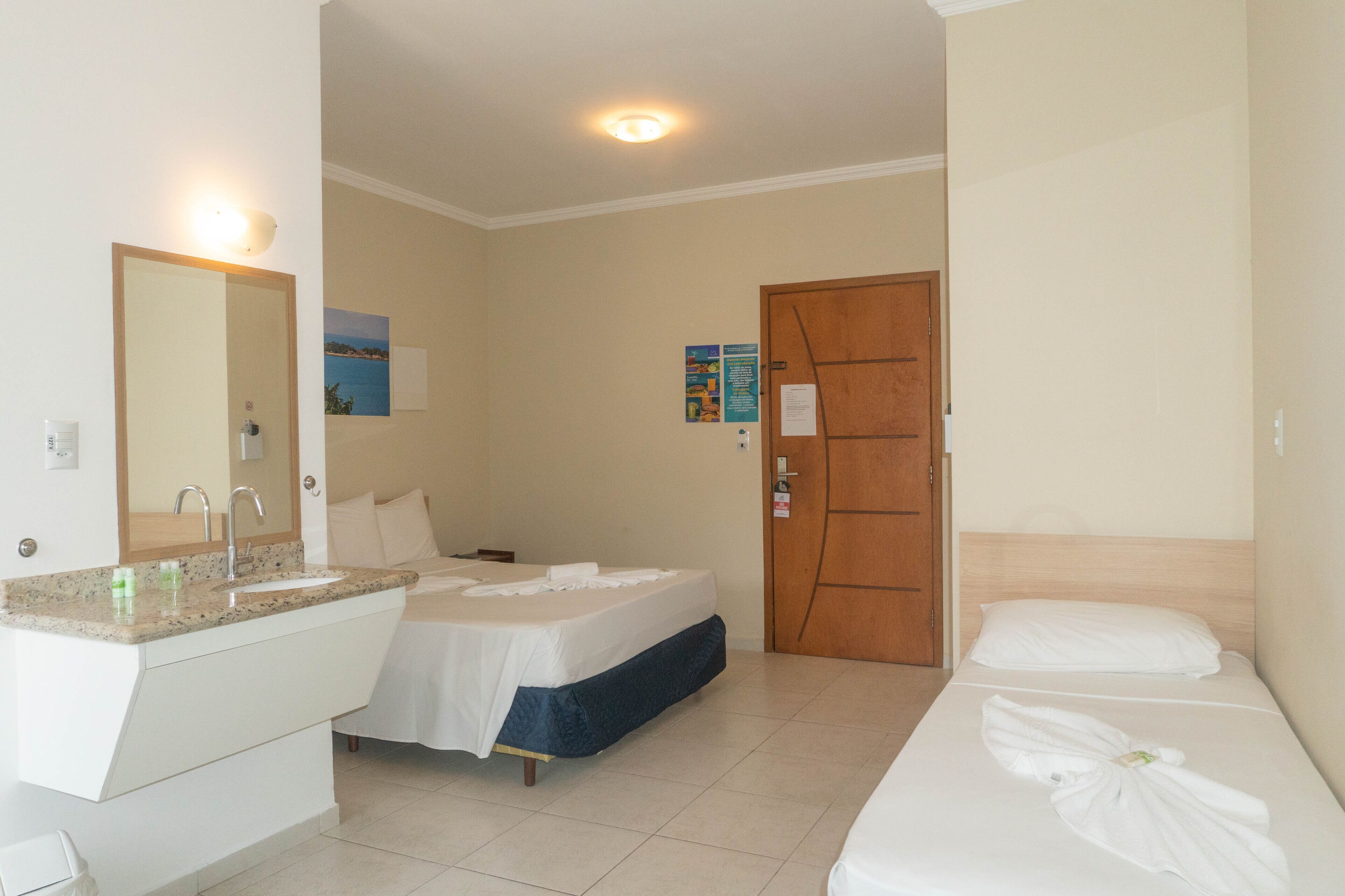 A hotel room with a bathroom, a bed, and a wooden door.