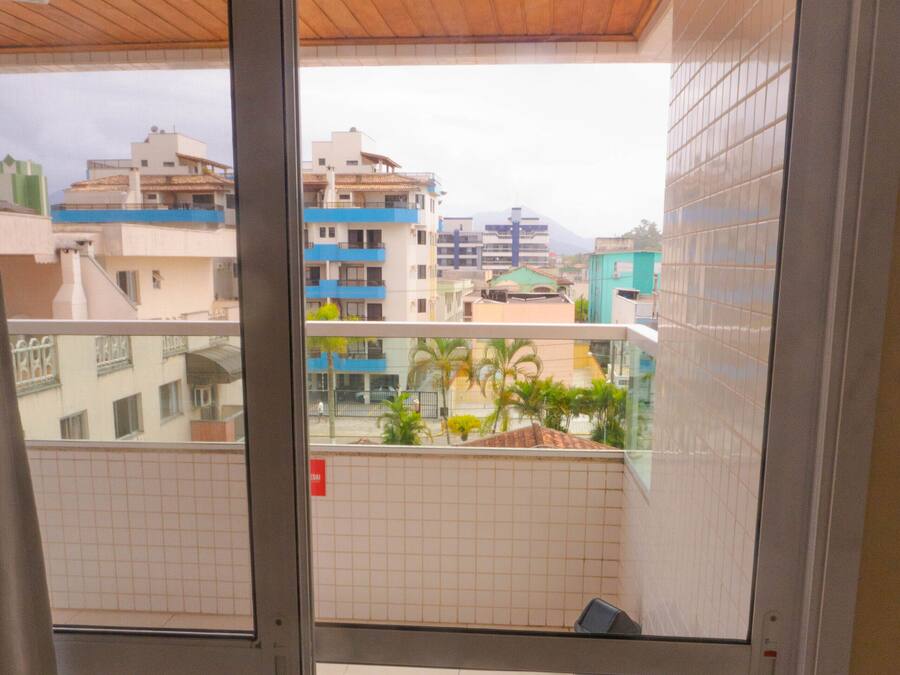 Varanda com piso de azulejos e vista para edifícios ao fundo.
