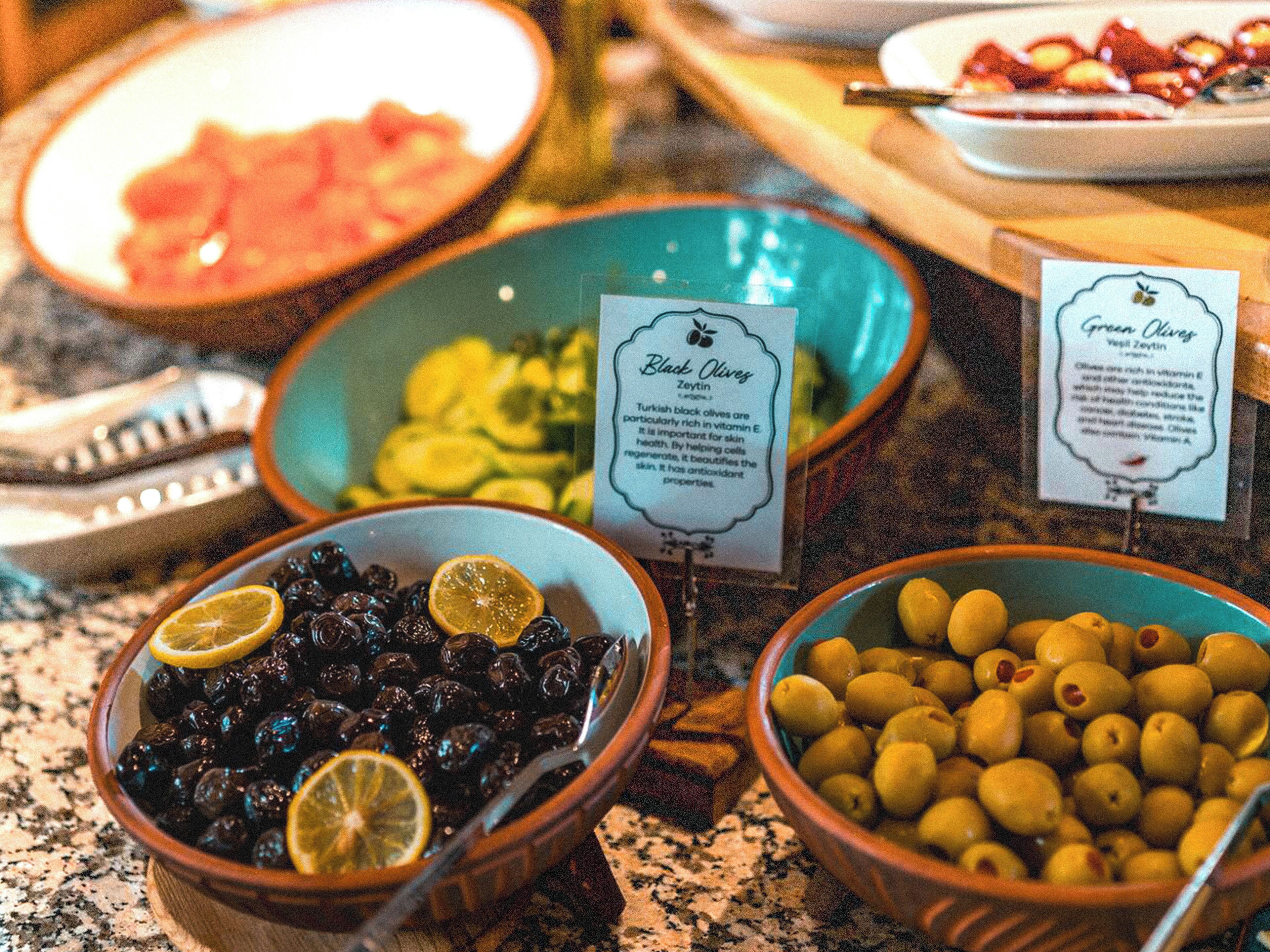 A buffet with bowls of black olives, green olives, and other dishes.