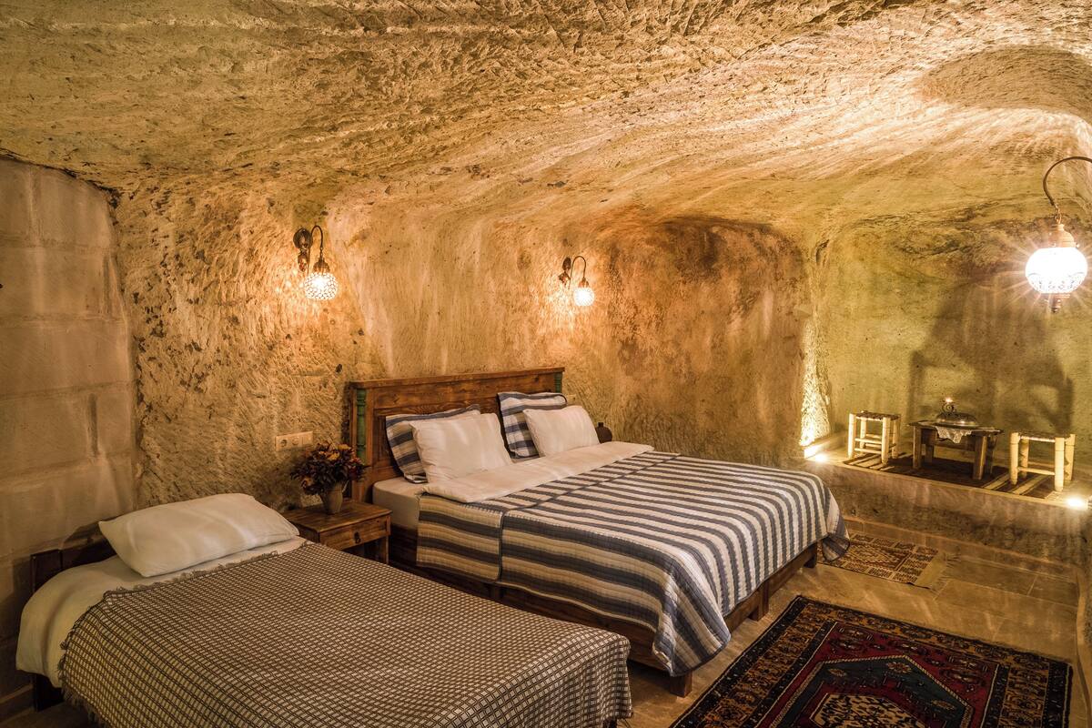 A rustic room with two beds, a wooden headboard, and a patterned rug.