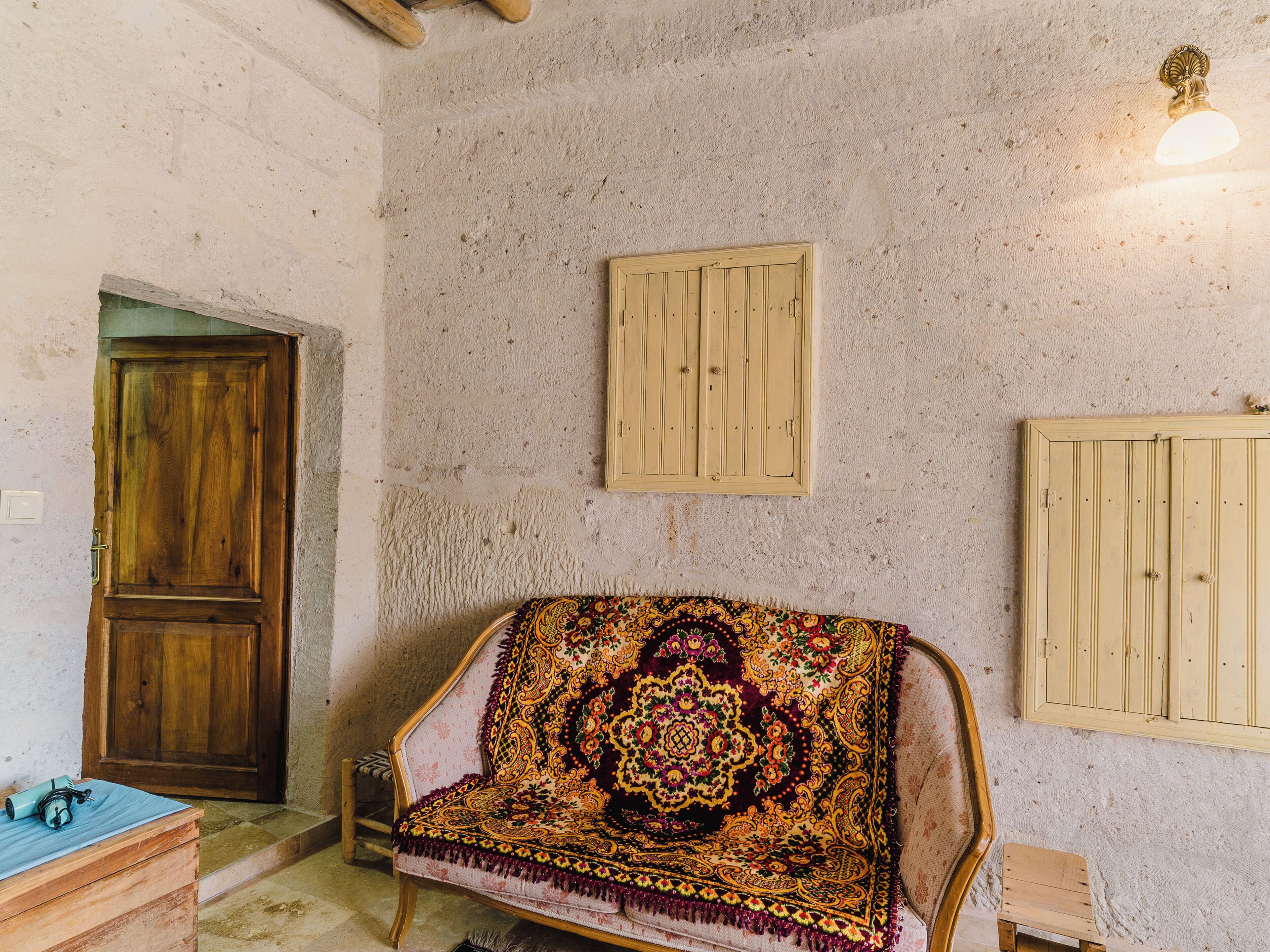 A room with a wooden door, a patterned sofa, and a wall-mounted light fixture.