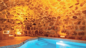 A stone-walled indoor pool with clear blue water and steps leading into it. - Atillas Cave Hotel (Nevsehir)