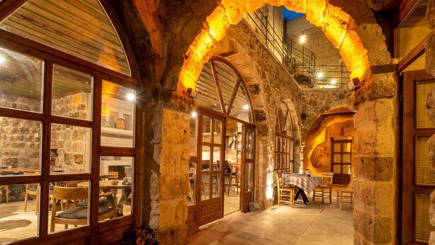 A stone-walled interior with wooden furniture and a staircase leading to an upper level. - Atillas Cave Hotel (Nevsehir)