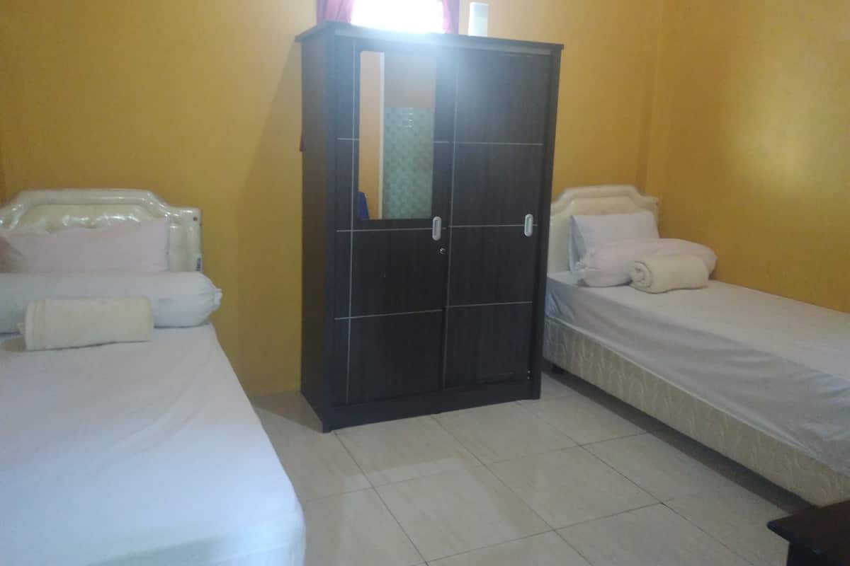 A room with two beds, a wardrobe, and a window with curtains.