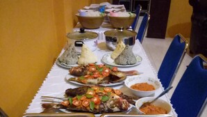 A buffet table with various dishes including seafood, salads, and rice. - Sinar Harapan (Tomia Island)
