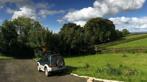 A car parked in a rural setting with green fields and trees in the background. - Kilcreeny Lodge (Lisburn)