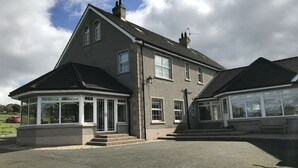 A two-story house with a covered porch and a large garage. - Kilcreeny Lodge (Lisburn)