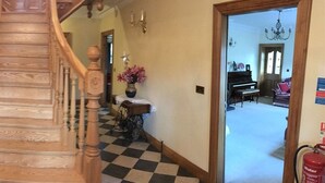 A wooden staircase leading to a room with a checkered floor, a piano, and a fire extinguisher. - Kilcreeny Lodge (Lisburn)