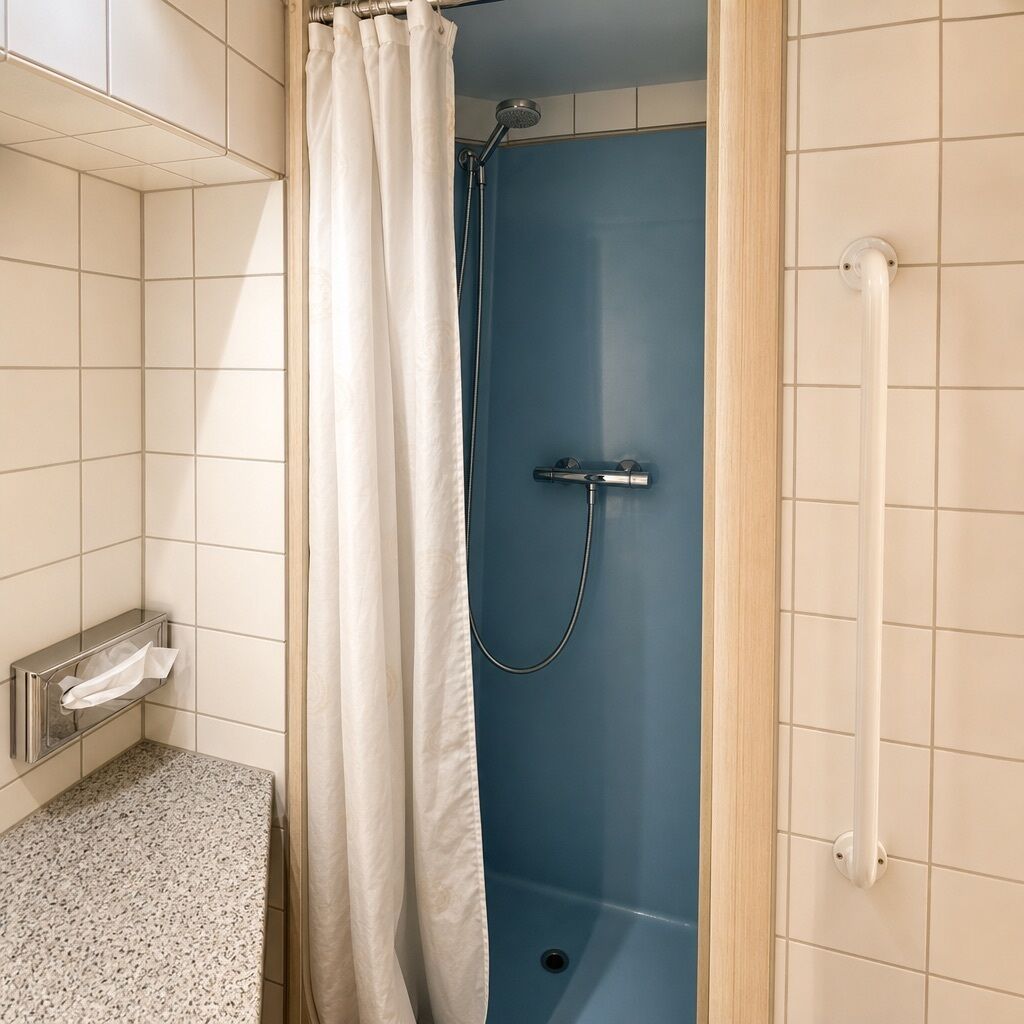 A shower area with a blue door, a white curtain, and a towel rack with a towel.