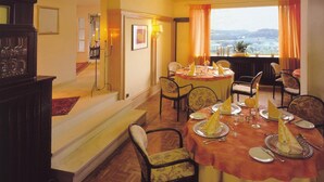 A dining area with a table set for four, chairs, a staircase, and a view of the outdoors. - Burghotel Volmarstein (Wetter)