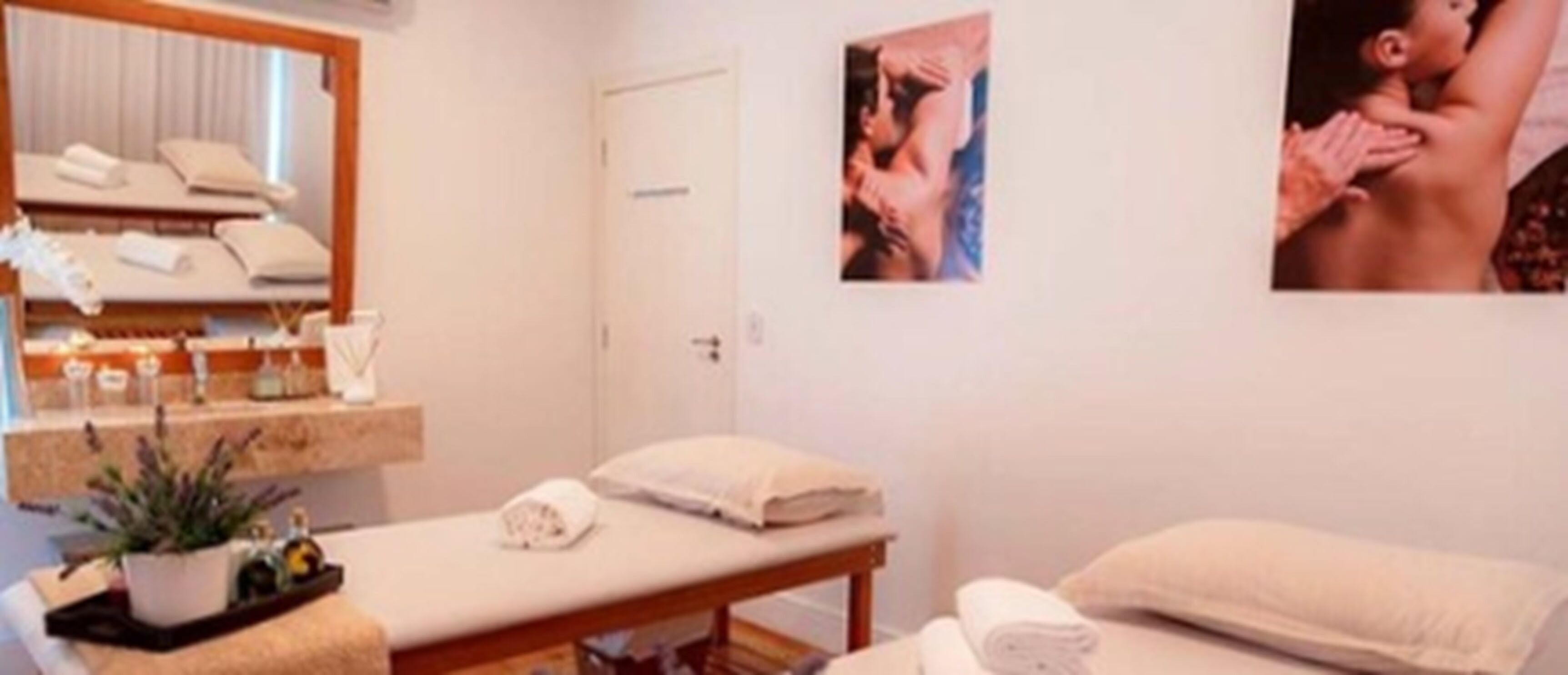 A spa room with a massage table, a small plant, and a mirror.