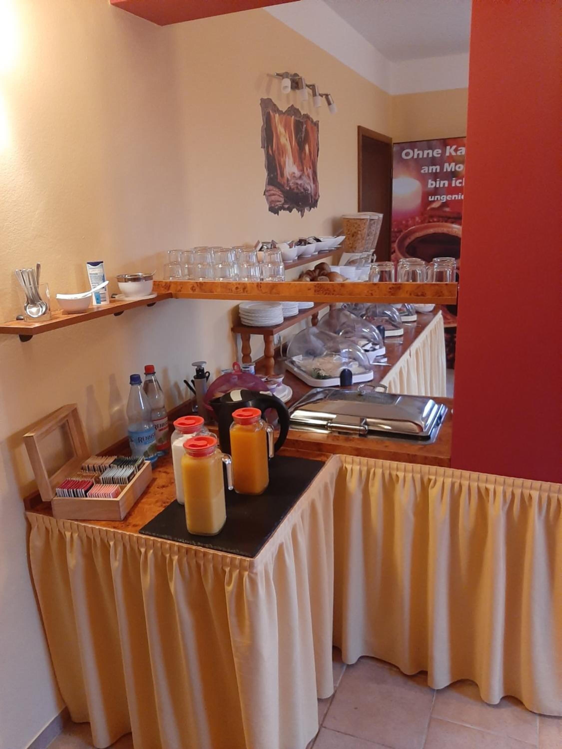 Morgenmadsbuffet med forskelligt mad, bestik og glas.