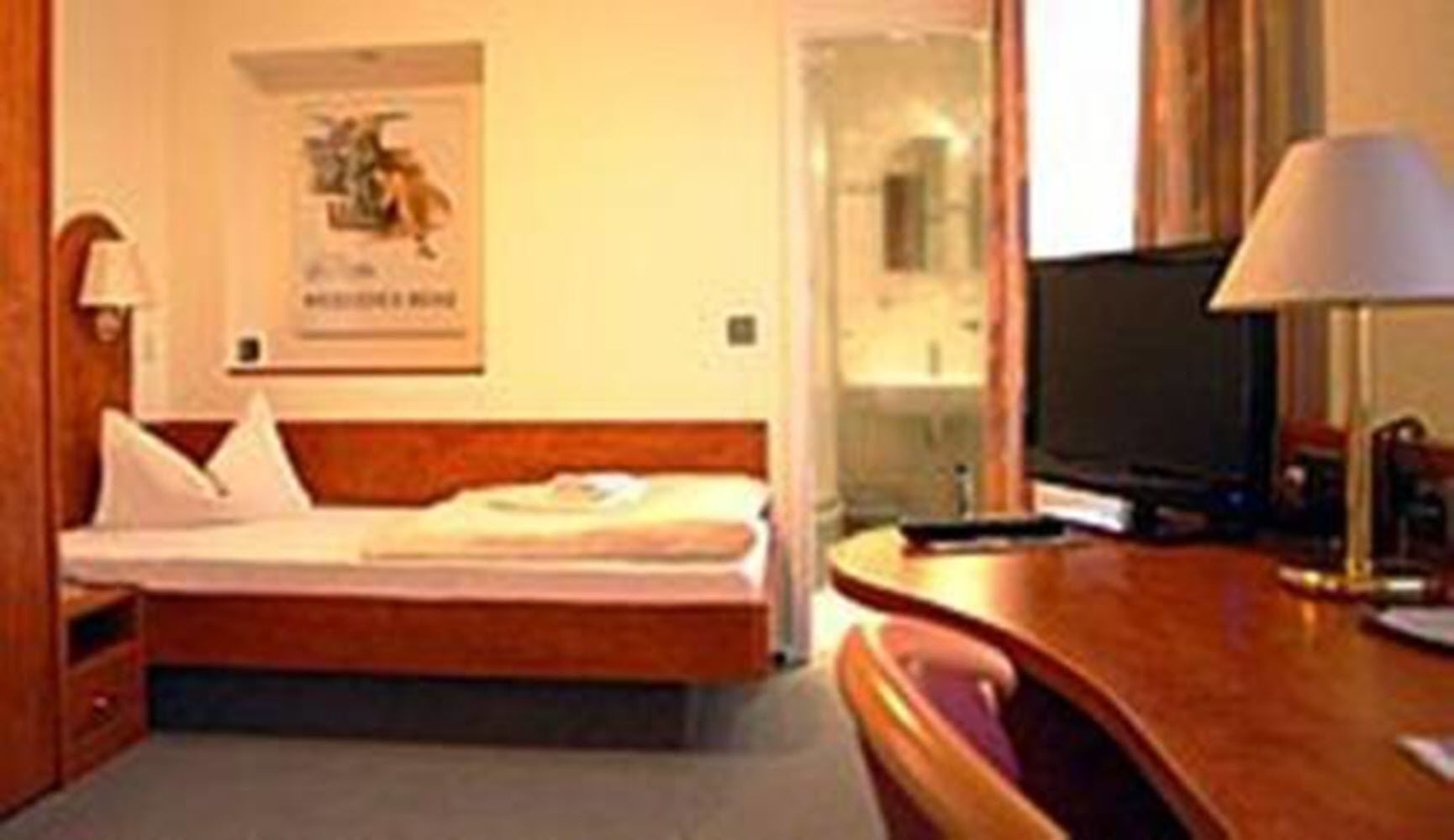 Une chambre d’hôtel avec un lit, un bureau, une télévision et une affiche au mur.