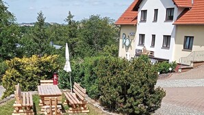 A hotel with a red-tiled roof, a signboard, and a small garden area with wooden benches and a fire hydrant. - Hotel Prox (Arnstadt)