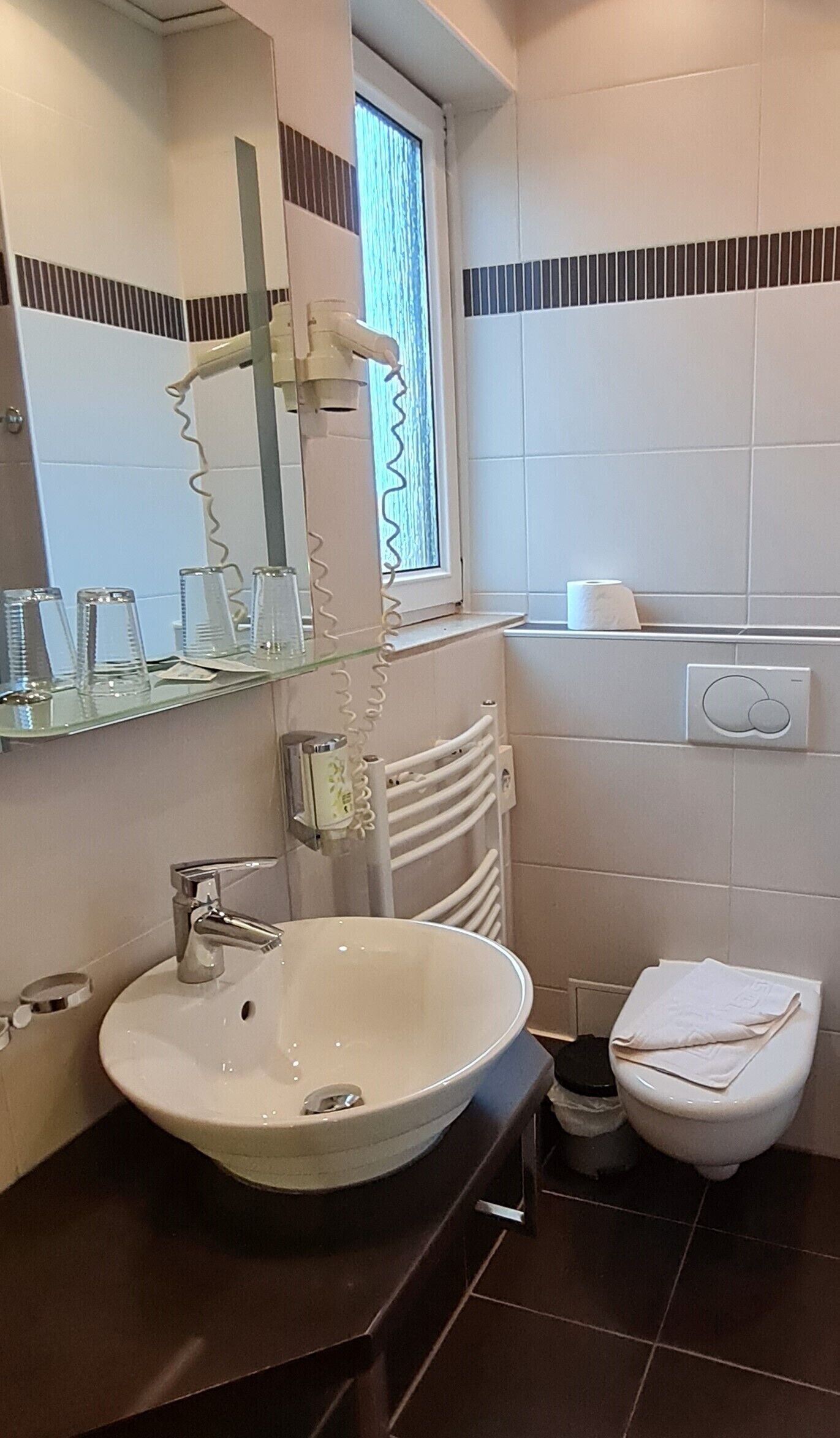 Un baño moderno con un lavabo redondo, un espejo, un perchero para toallas y un inodoro.