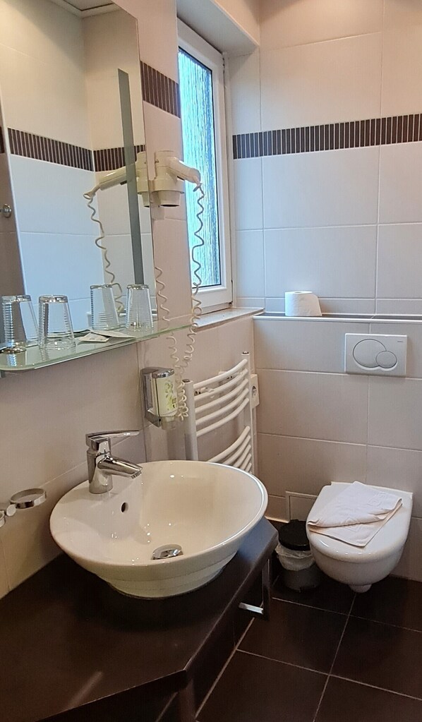 Un baño moderno con un lavabo redondo, un espejo, un perchero para toallas y un inodoro.