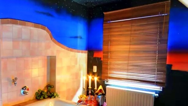 A bathroom with a bathtub, a window with blinds, and a wall with a starry design. - Hotel Prox (Arnstadt)