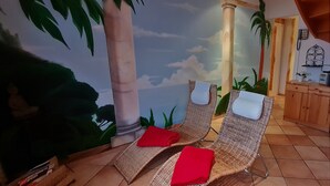 A room with two wicker lounge chairs, a red towel on each, and a mural of a tropical scene with palm trees and a beach. - Hotel Prox (Arnstadt)