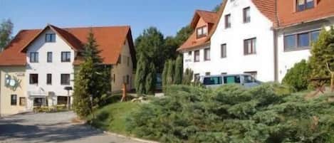 A row of two-story buildings with red-tiled roofs, likely residential or small hotel buildings, with a paved driveway in front.