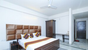 A modern bedroom with a large bed, a wardrobe, a desk, and a ceiling fan. - Hotel Datt Residency (Jabalpur)