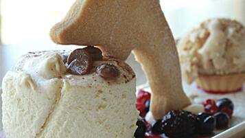 A dessert with a cookie shaped like a number one, a cupcake, and berries on a plate.