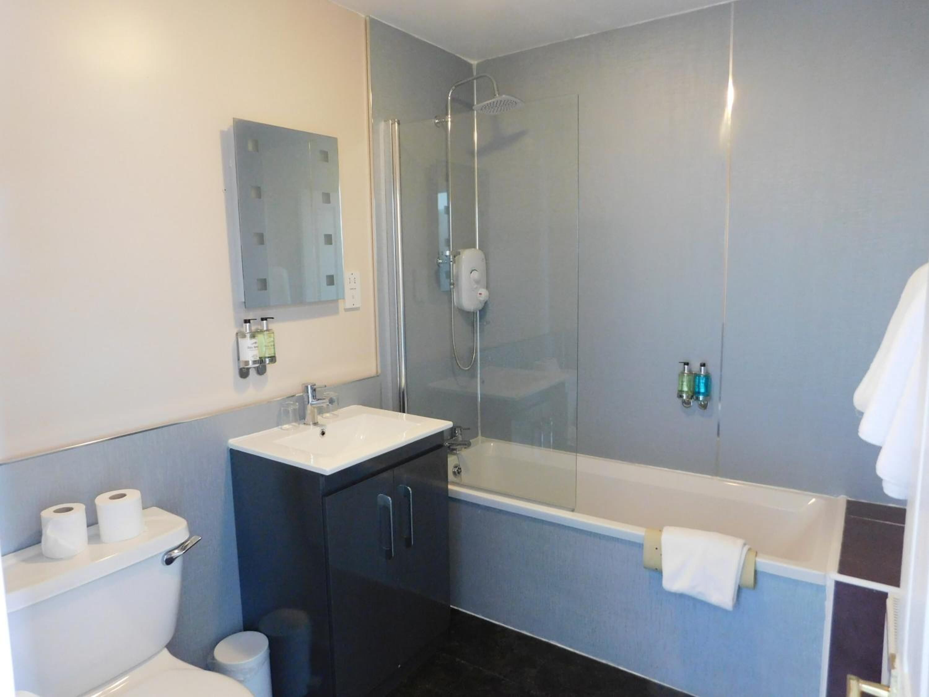 A modern bathroom with a glass-enclosed shower, a white sink, and a bathtub.