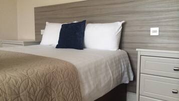 Quarto de hotel com cama, mesa de cabeceira e cômoda.