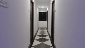 A hallway with a checkered floor, white walls, and doors on either side. - OYO 15776 V R Residency (Bengaluru)