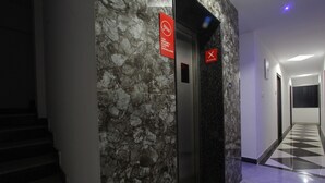 A hallway with a marble wall, a no-smoking sign, and a no-smoking sign on the floor. - OYO 15776 V R Residency (Bengaluru)