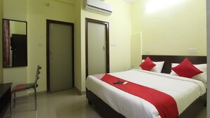 A hotel room with a bed, a chair, a desk, and an air conditioning unit. - OYO 15776 V R Residency (Bengaluru)