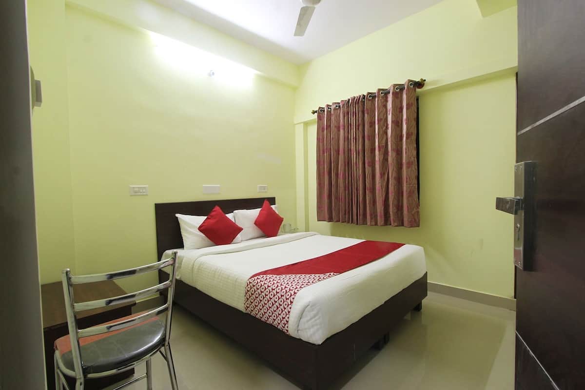 A room with a bed, a chair, a curtain, and a door.