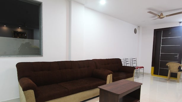 A living room with a brown sofa, a wooden coffee table, and a ceiling fan. - OYO 15776 V R Residency (Bengaluru)