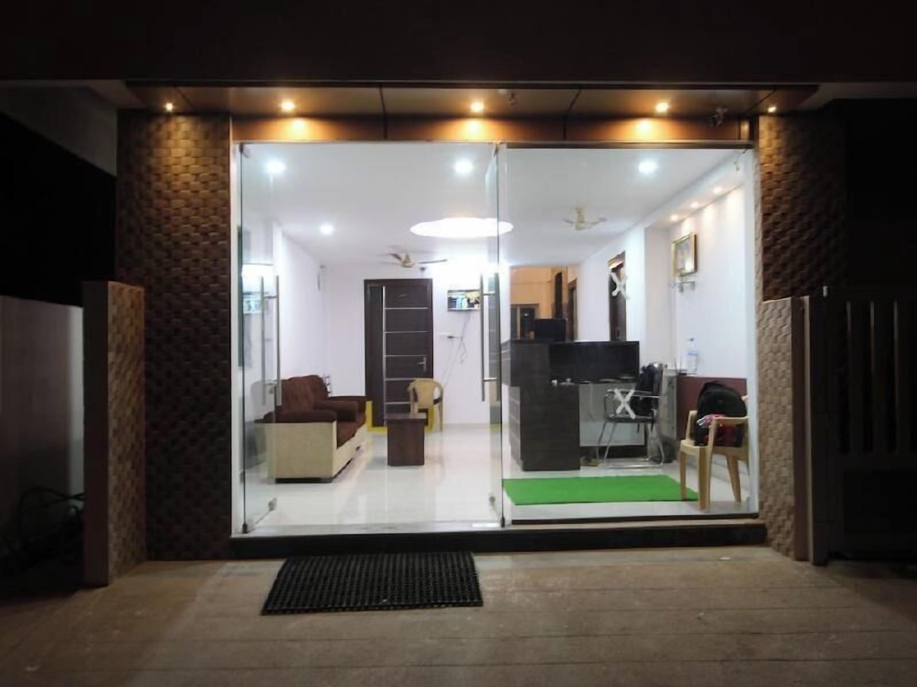 A hotel entrance with a glass door, a reception desk, and a seating area inside.