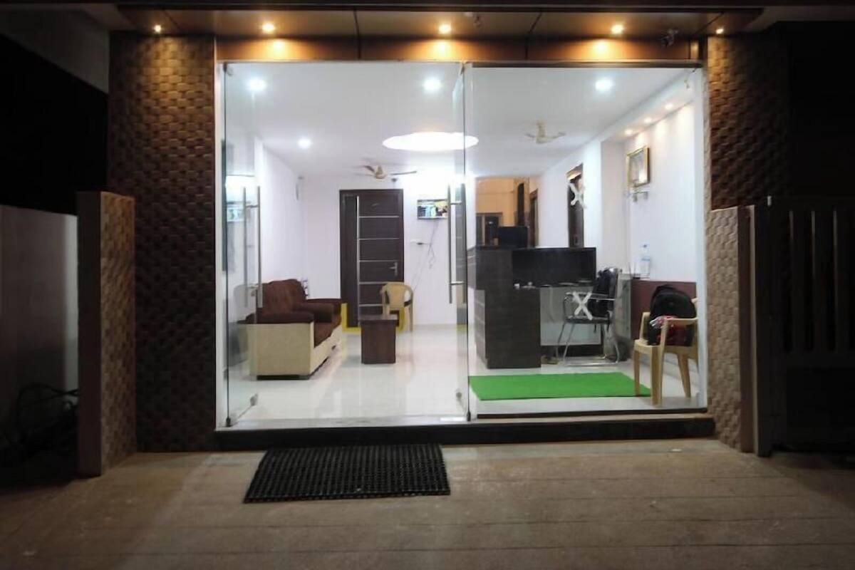 A hotel entrance with a glass door, a reception desk, and a seating area inside.