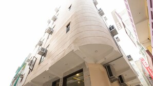 A multi-story building with a curved facade, air conditioning units, and a visible entrance. - OYO 16375 Melfort Inn (New Delhi)