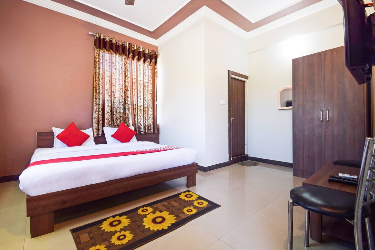 Quarto de hotel com cama, escrivaninha, cadeira, guarda-roupa e porta.