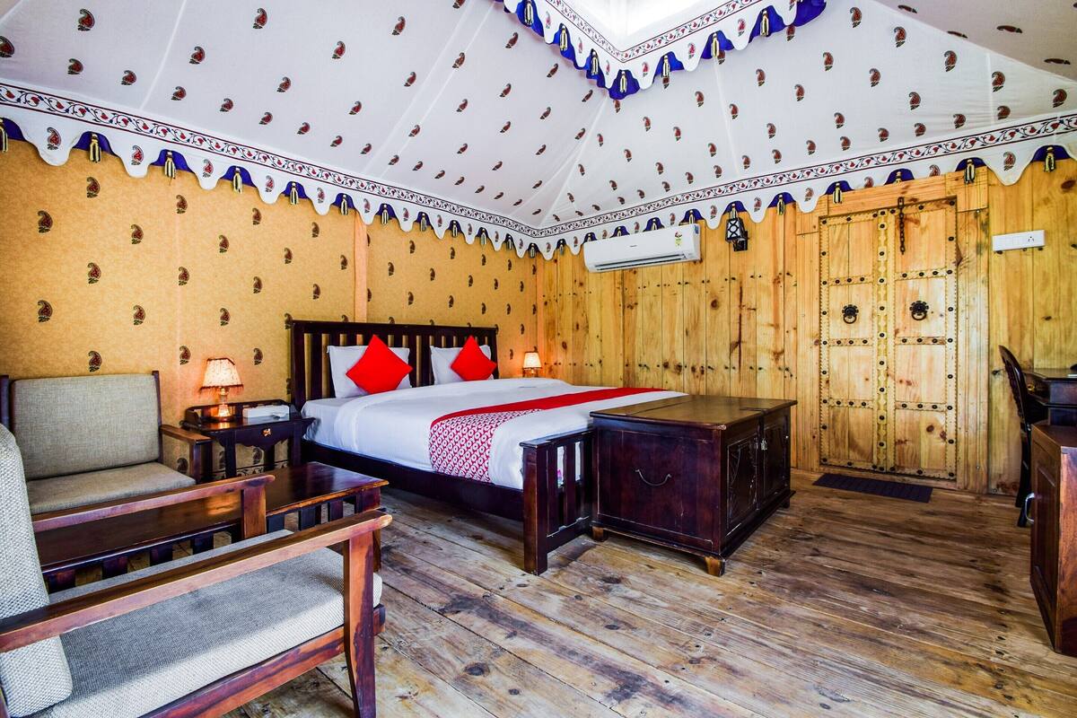 Um quarto com uma cama, uma cadeira, uma mesa de cabeceira e um guarda-roupa de madeira.