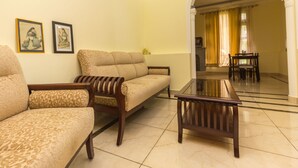 A living room with a sofa, armchairs, and a coffee table. There are framed pictures on the wall and a dining area in the background. - OYO 16593 Home Luxury 3BHK Galaxy Villa Andrar (Dharamshala)