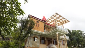 A two-story house with a balcony, a red roof, and a brick exterior. - OYO 16593 Home Luxury 3BHK Galaxy Villa Andrar (Dharamshala)