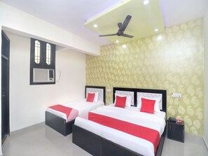 Habitación de hotel con dos camas, ventilador de techo y papel tapiz estampado.