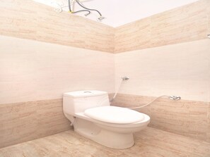 Un baño con inodoro, ducha y paredes de azulejos.