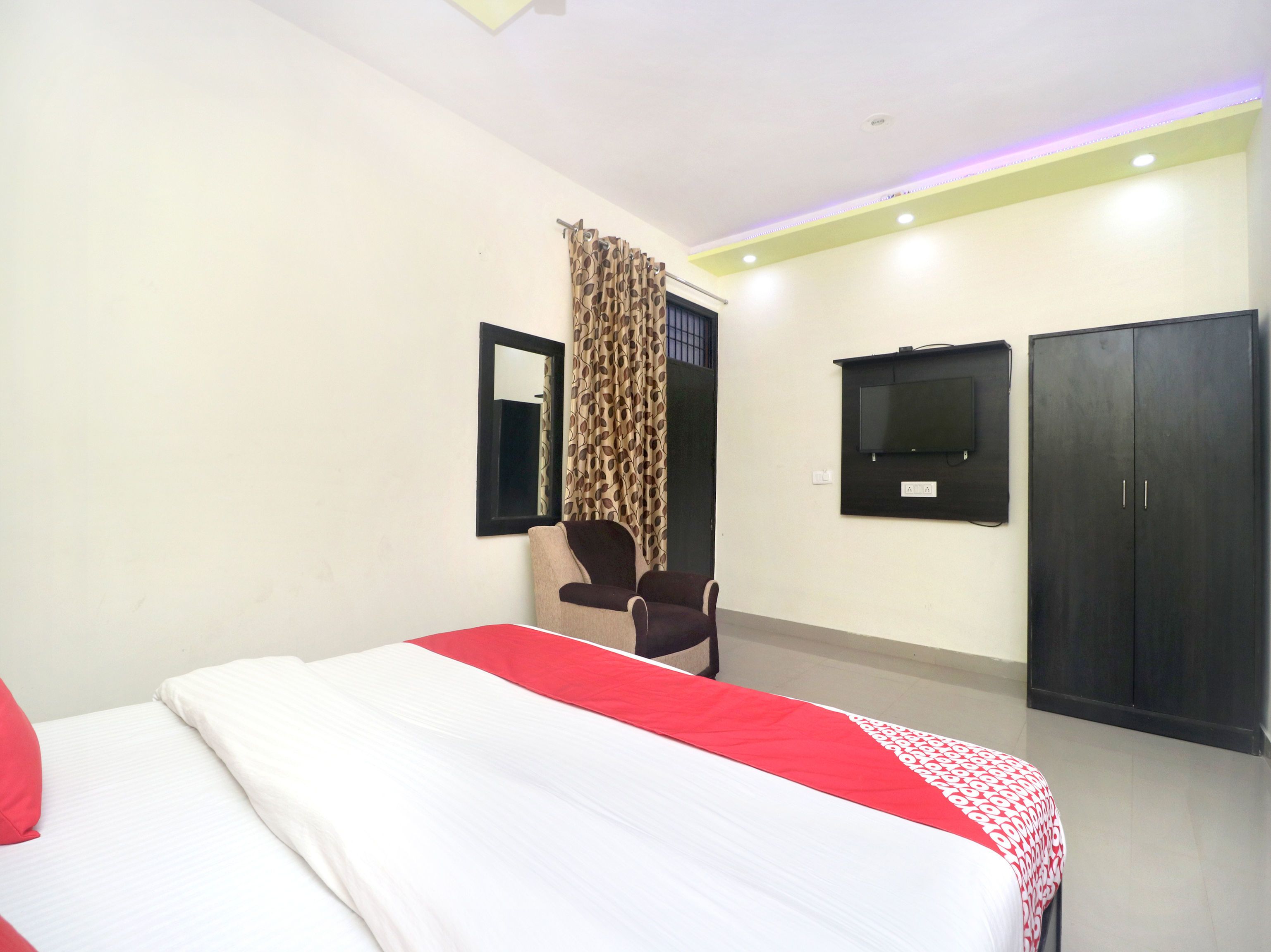 Una habitación de hotel con cama, escritorio, silla, televisión y armarios.