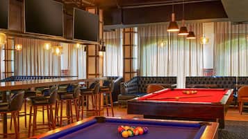 A pool table with balls, a bar area with stools, and a seating area with a pool table.