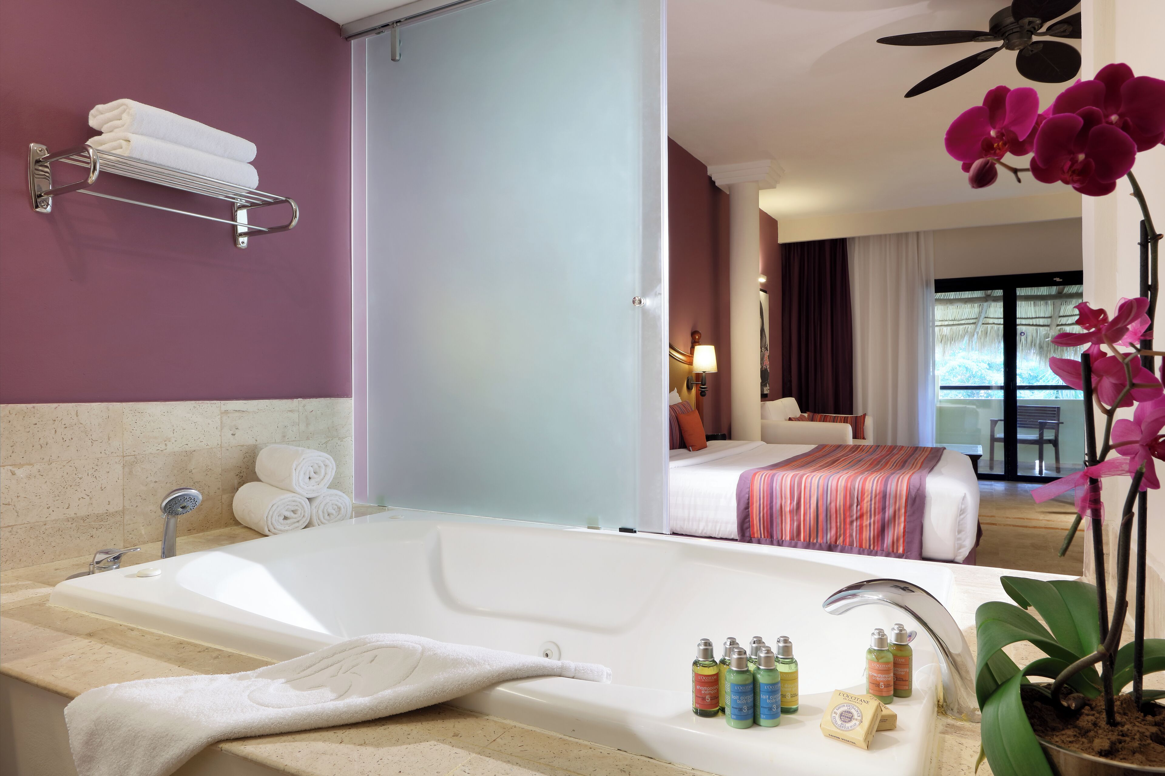 Un baño de hotel con una bañera grande, un perchero y artículos de aseo en el borde.